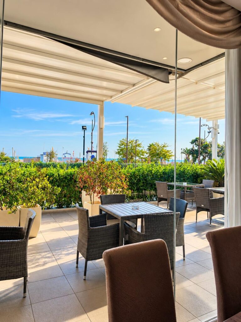Veranda esterna con tavoli e vista mare della sala colazioni del Club House Hotel